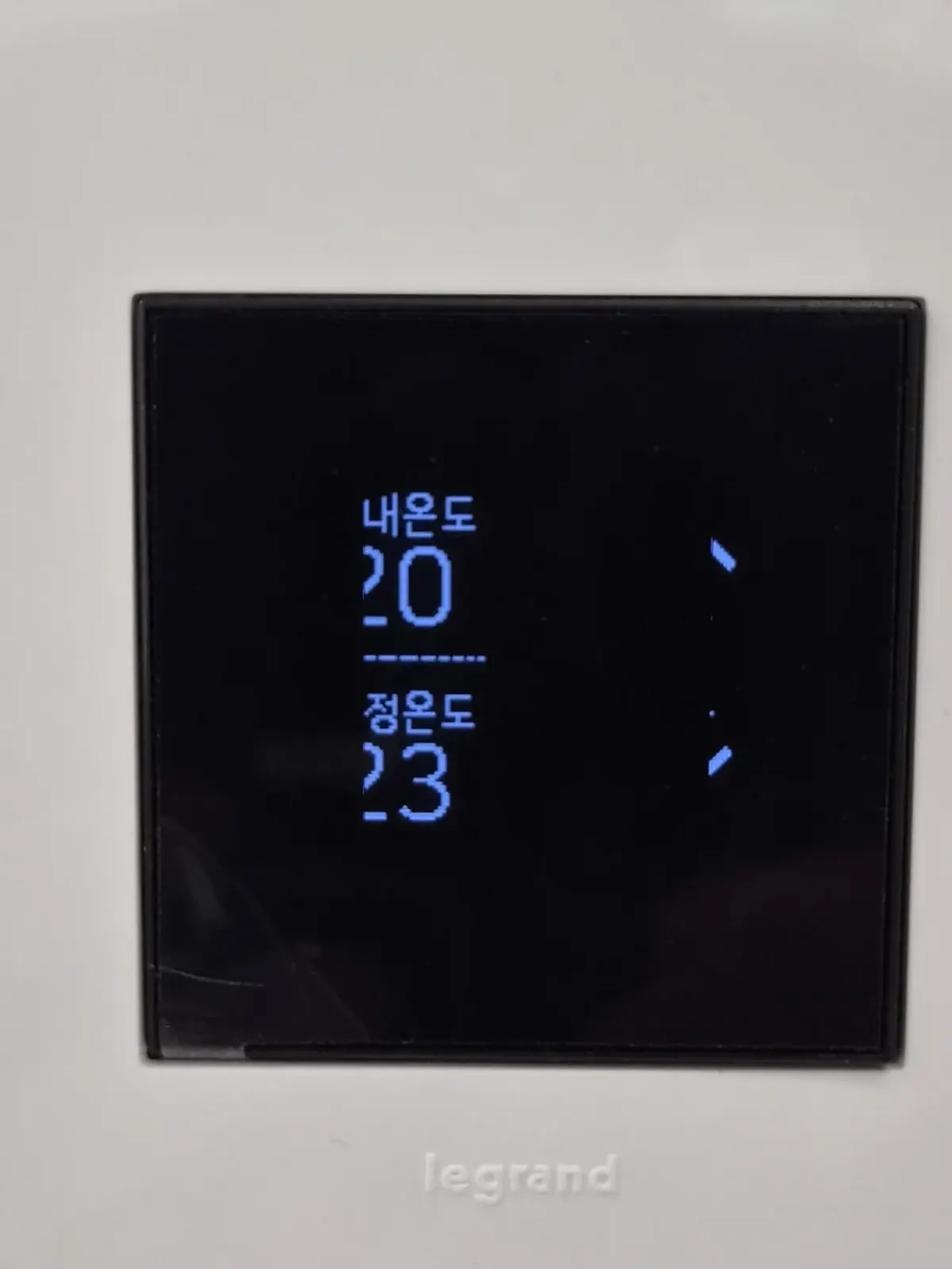 화이트 플레이트 중앙 르그랑아테오 온도조절기 화면 근접 사진, 현재온도와 설정온도 표시